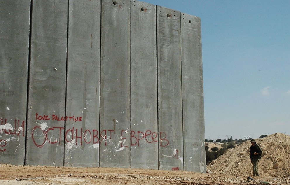 חייל ישראלי ליד מקטע לא גמור בגדר ההפרדה, 2004   מקור: ויקיפדיה (ג'סטין מקינטוש)